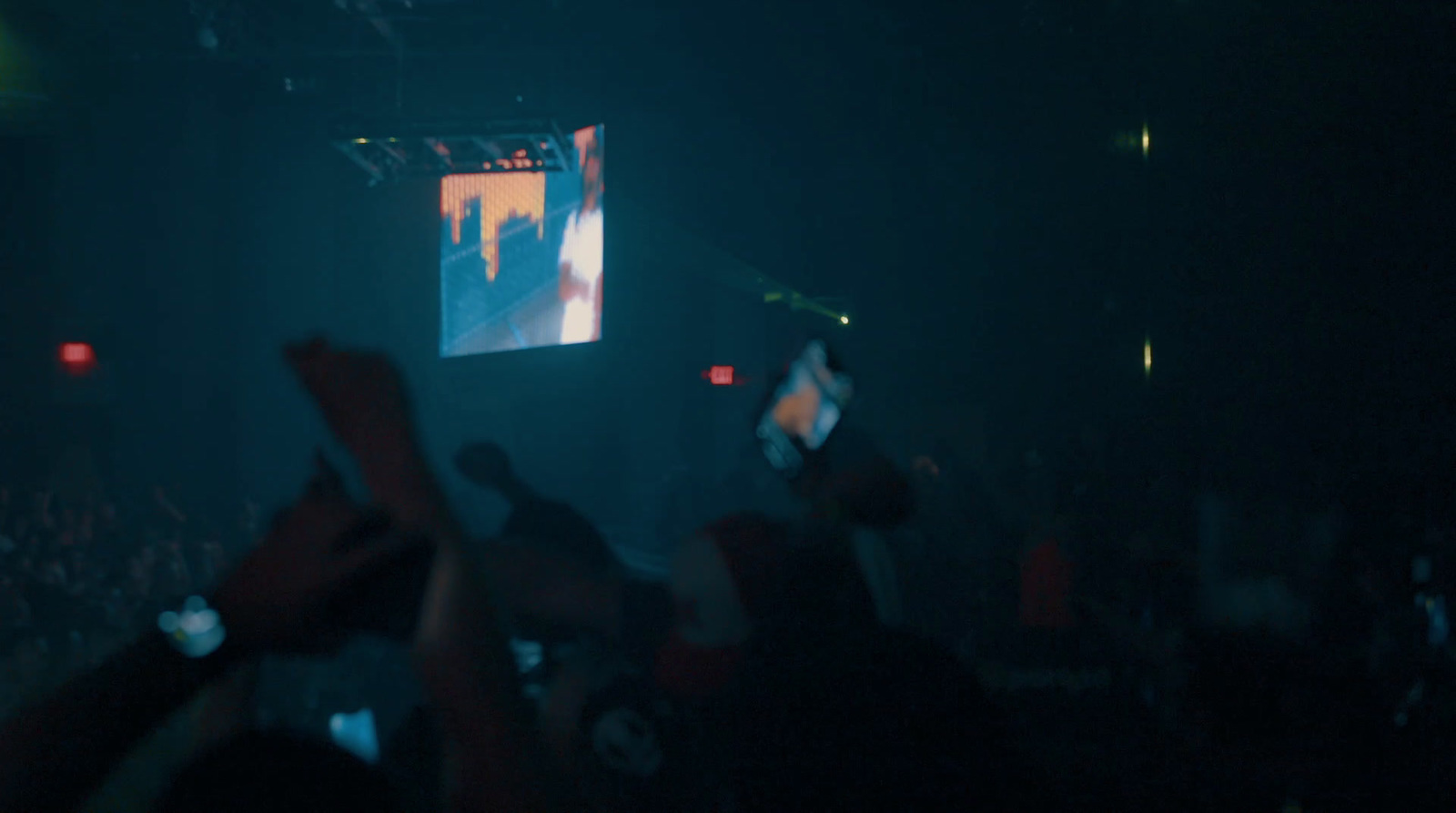 a crowd of people at a concert with their hands in the air