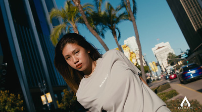 a woman standing on the side of a road next to palm trees