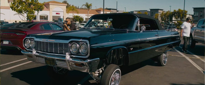 a black car parked in a parking lot next to other cars