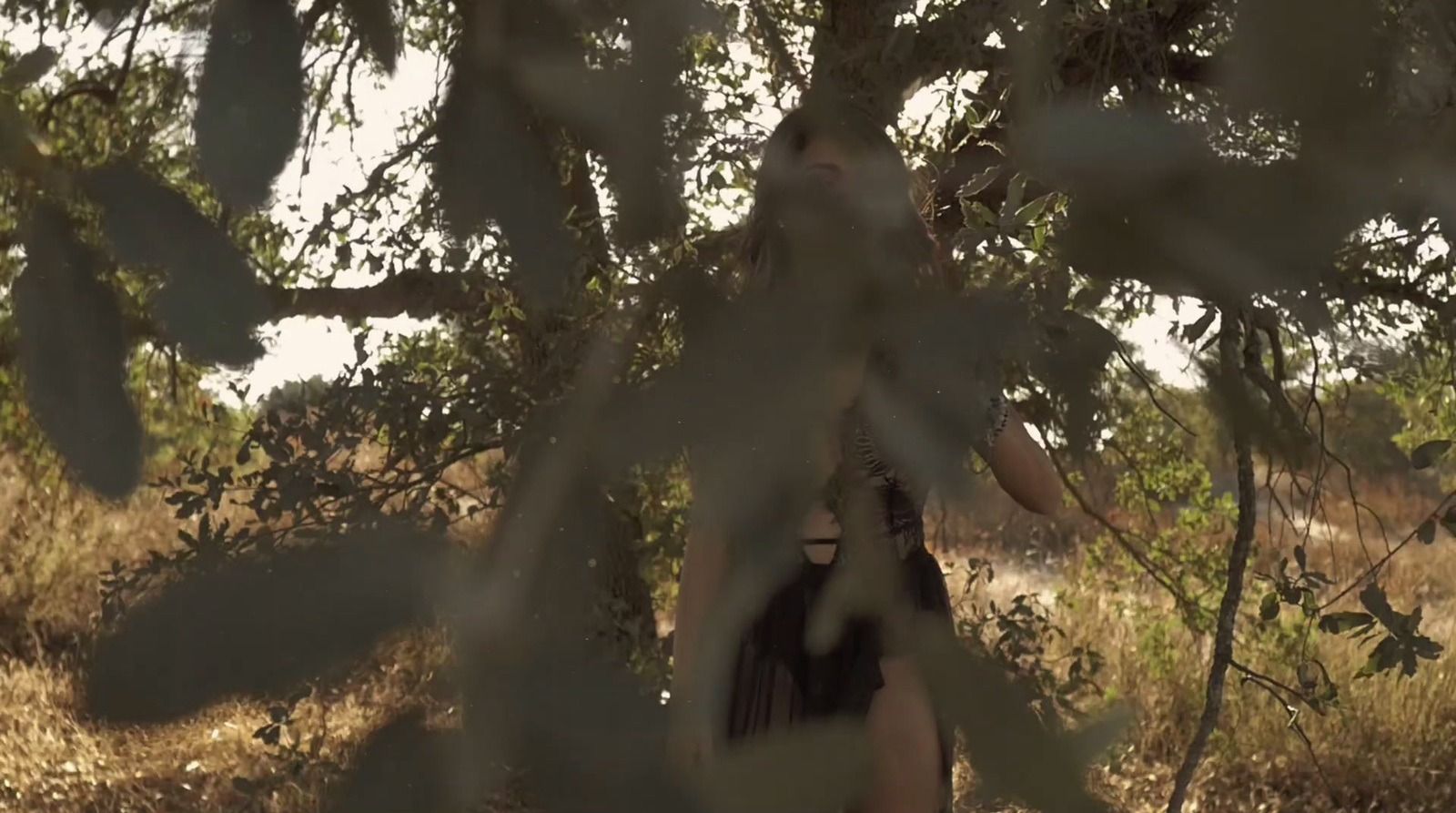 a woman standing under a tree in a field