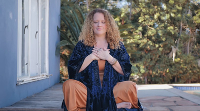 a woman sitting on the ground with her hands folded