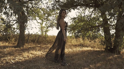 a woman standing in a field next to trees