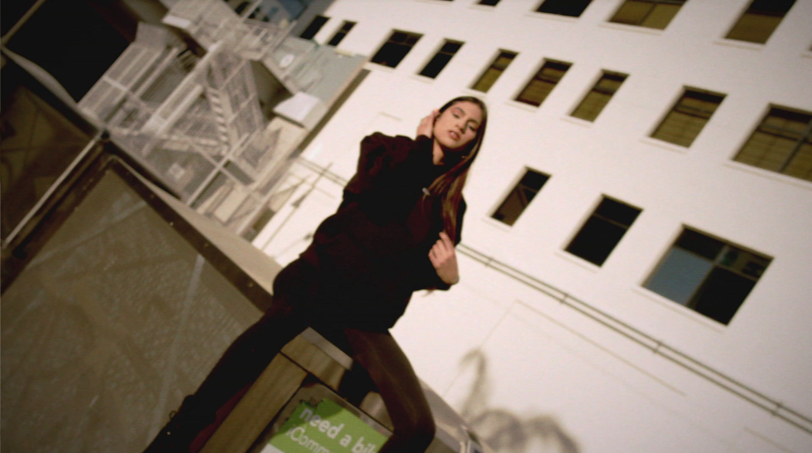 a woman standing on a ledge talking on a cell phone