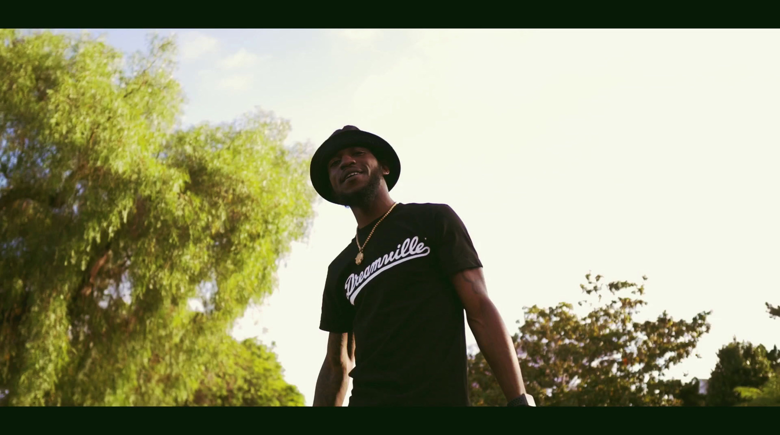 a man in a black shirt and hat holding a skateboard