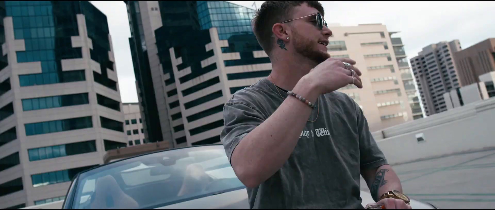 a man standing next to a car in front of tall buildings