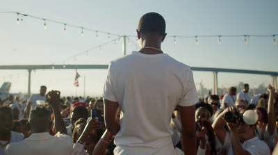 a man in white shirt standing in front of a crowd of people