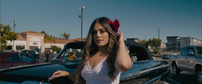 a woman standing next to a car in a parking lot