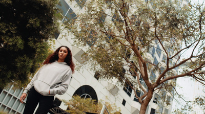 a woman standing next to a tree in front of a building