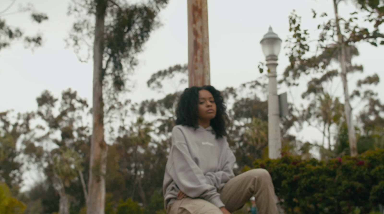 a woman sitting on top of a wooden pole