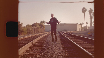 a man standing on a train track with palm trees in the background