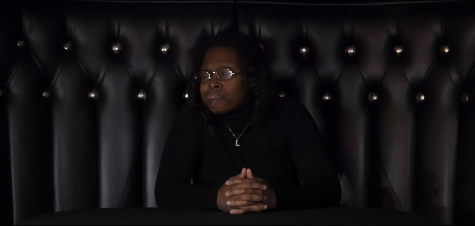 a woman sitting at a table in front of a black wall