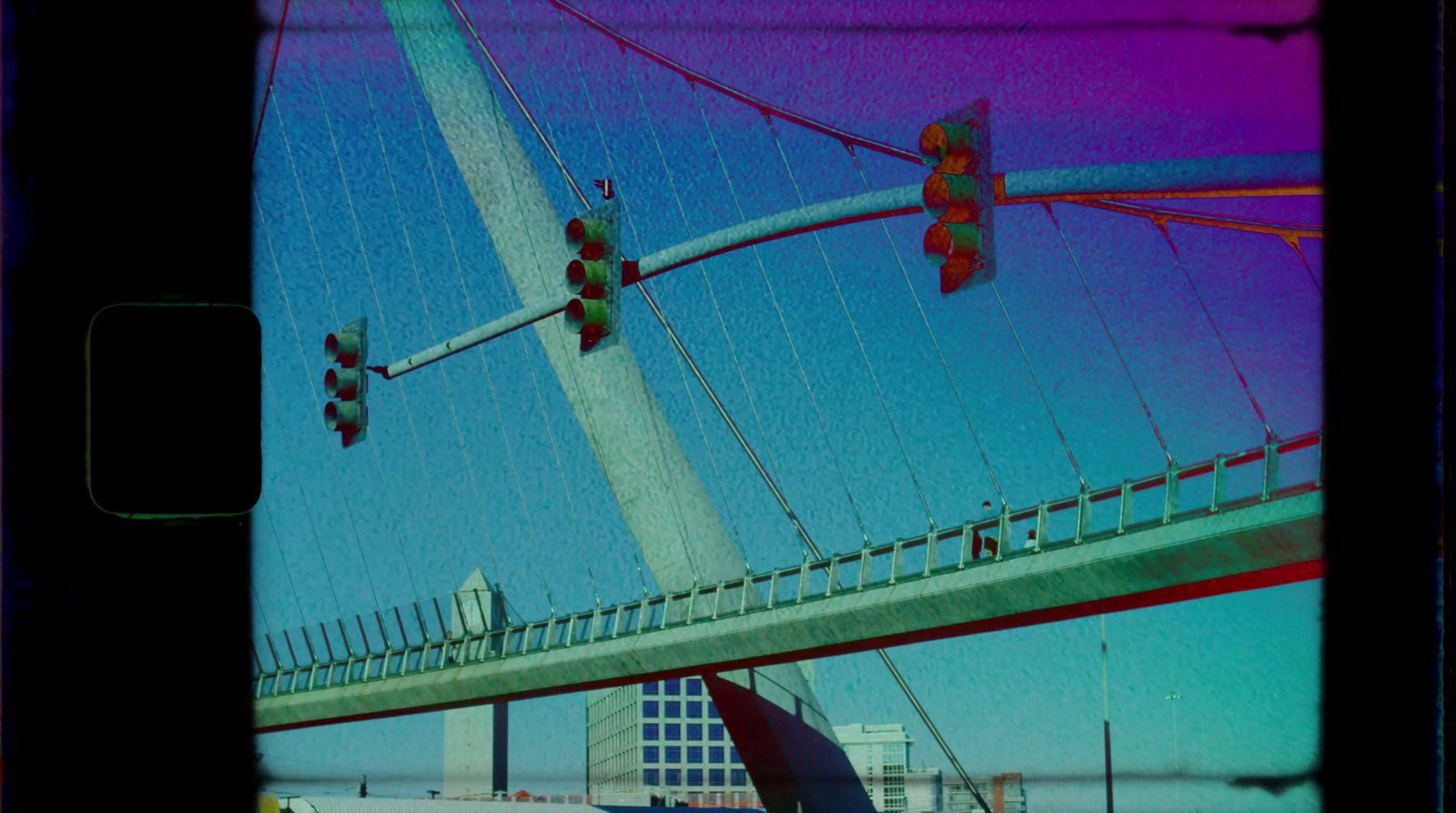 a traffic light hanging over a bridge next to a tall building