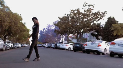 a man riding a skateboard down a street next to parked cars