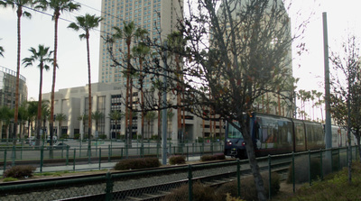 a train traveling down tracks next to a tall building