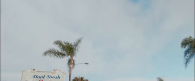 a street sign with palm trees in the background