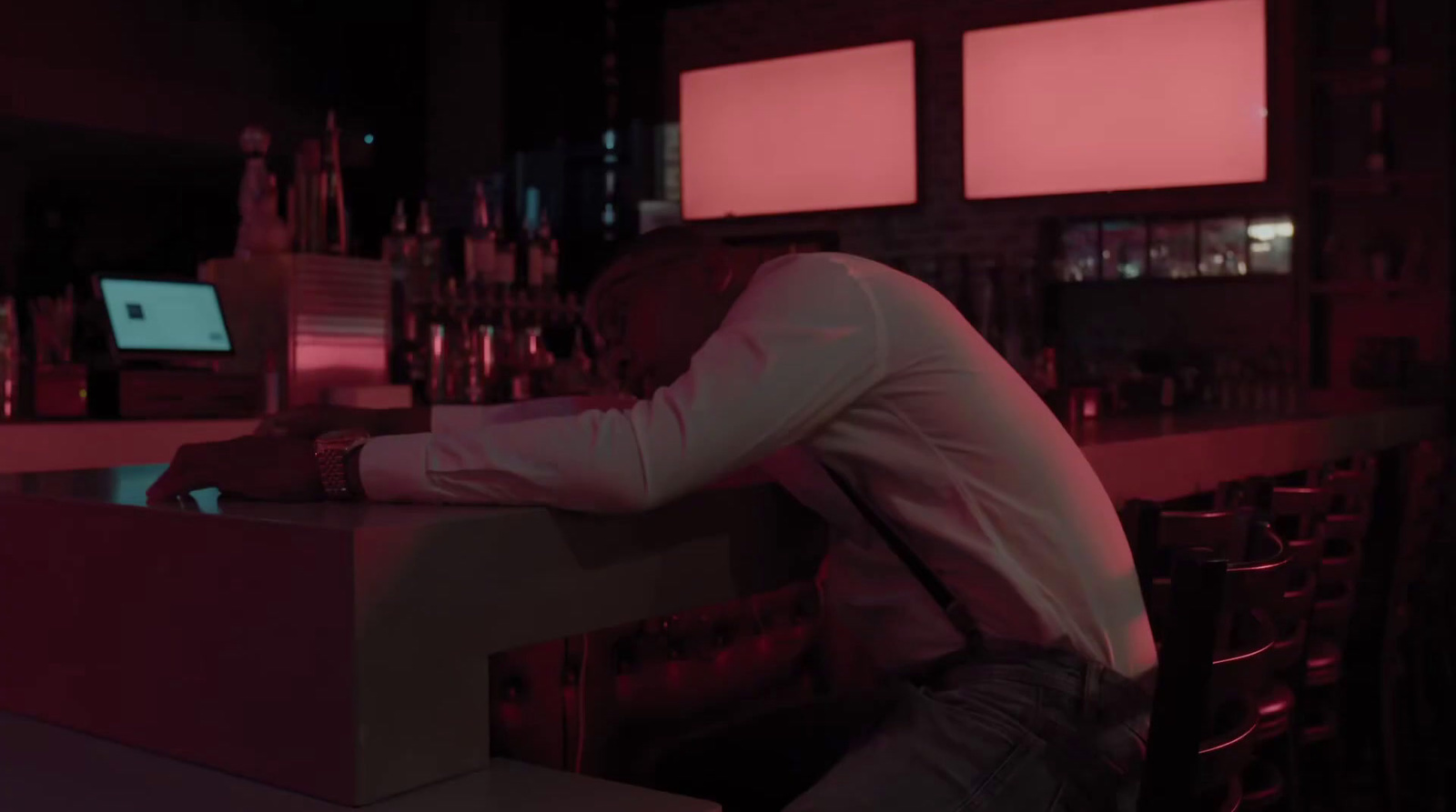 a man sitting at a bar in a white shirt