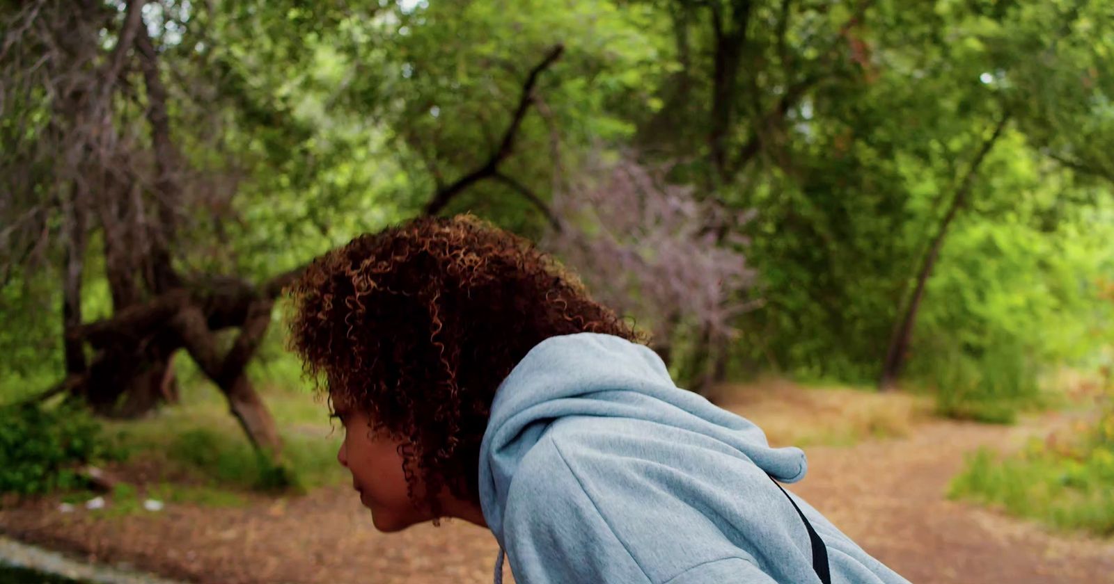 a woman in a blue hoodie riding a skateboard