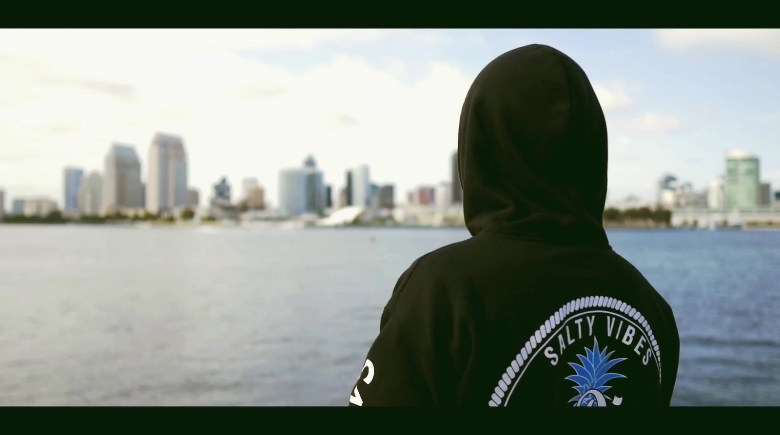 a person wearing a hoodie looking out over a body of water