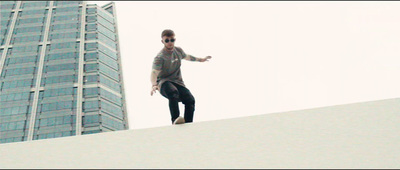 a man standing on top of a roof next to a tall building