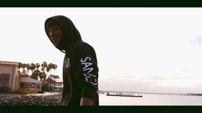 a man in a hoodie is standing by the water