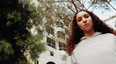 a woman with curly hair wearing a grey hoodie