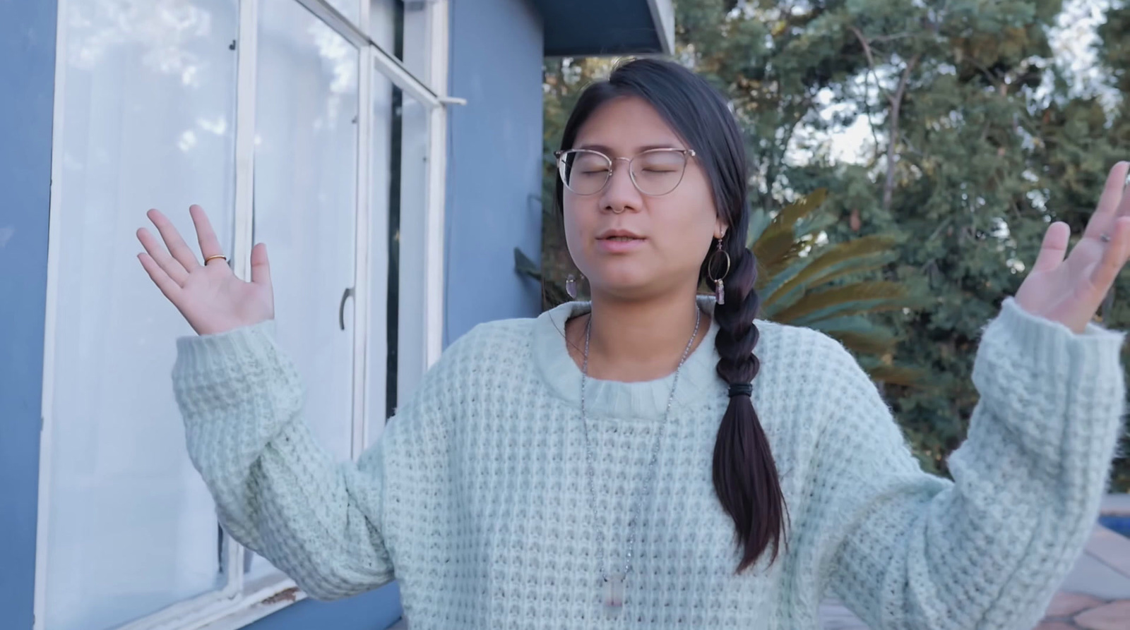 a woman wearing glasses standing in front of a window