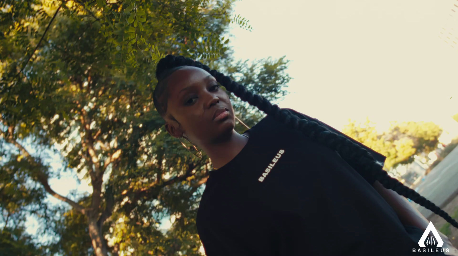 a man with braids standing in front of a tree