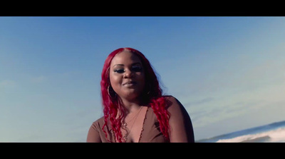 a woman with long red hair standing in front of the ocean