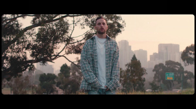 a man standing in front of a tree with a city in the background