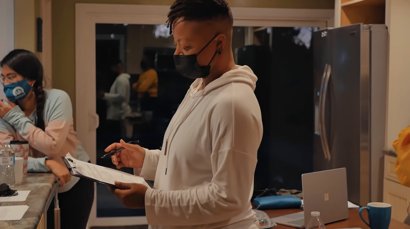 a man wearing a face mask while standing in a kitchen