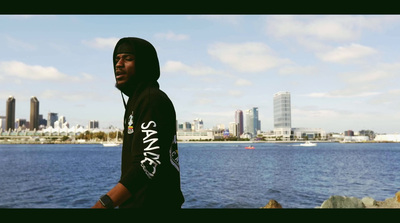 a man in a hoodie standing by a body of water