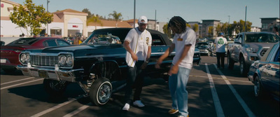 a couple of men standing next to a parked car