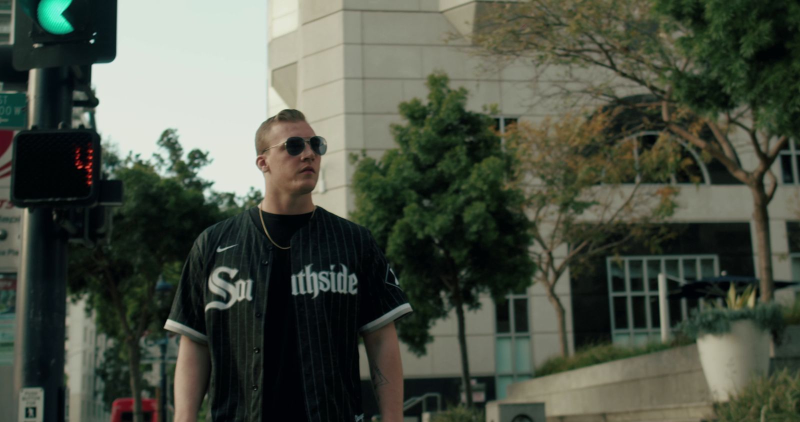 a man in a black shirt and sunglasses walking down a street