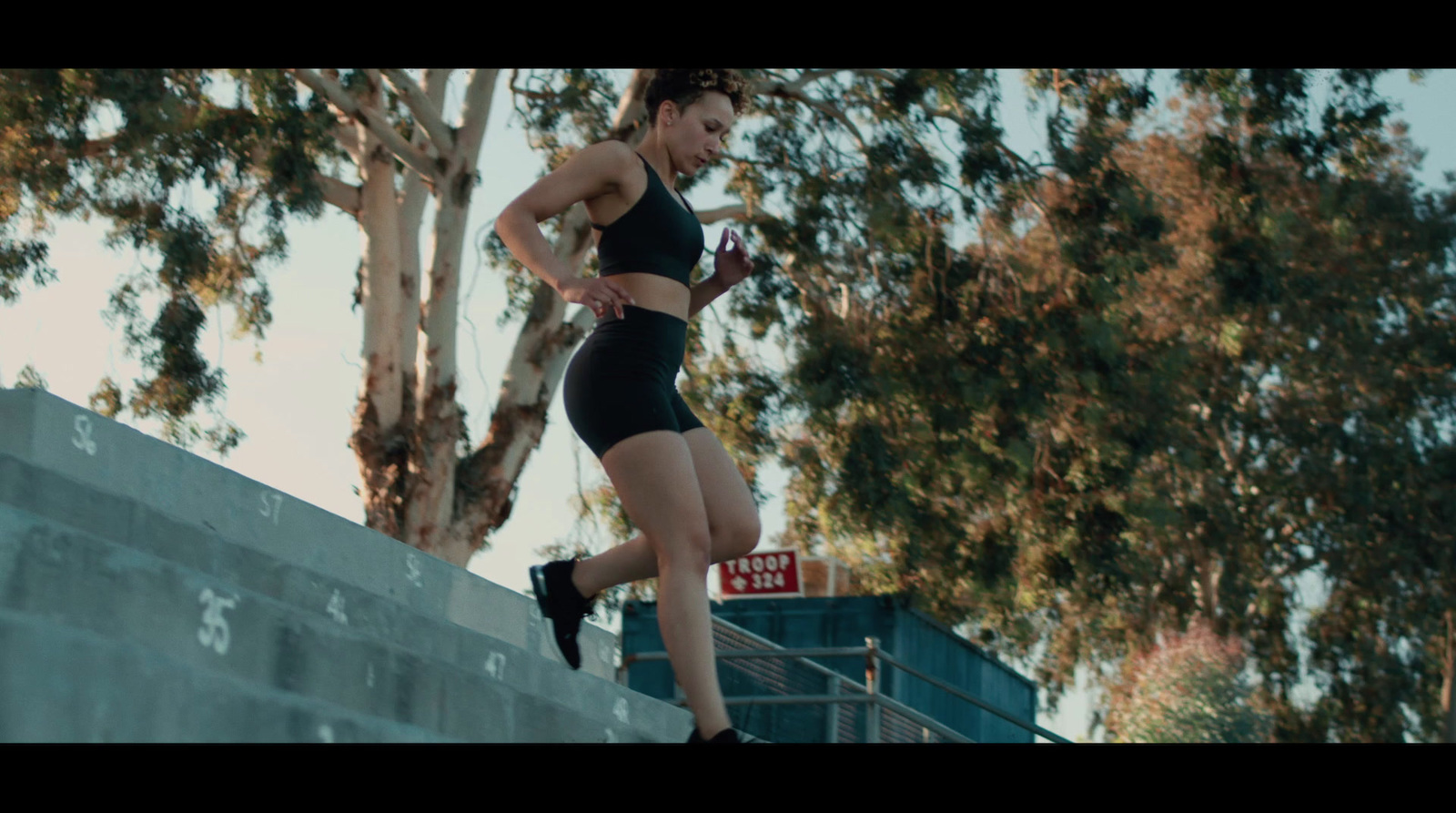 a woman running up a ramp with trees in the background