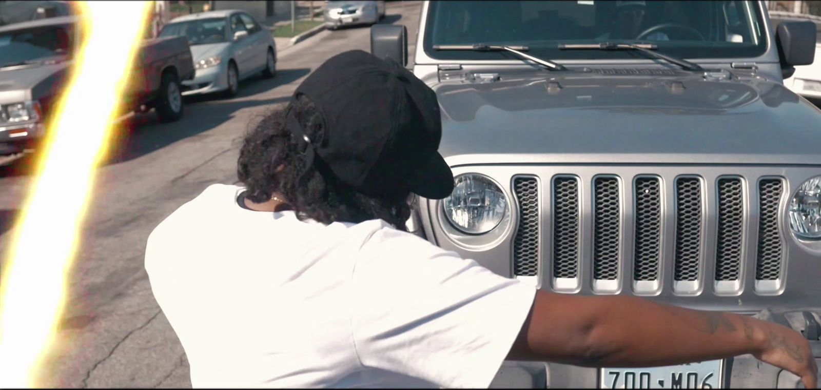 a man in a black hat leaning on a silver jeep