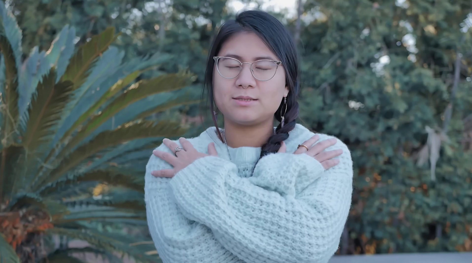 a woman wearing glasses standing in front of a palm tree