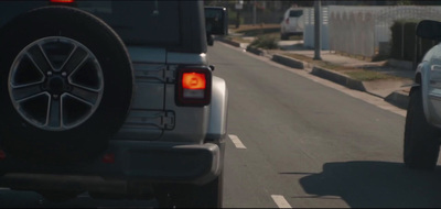 a white jeep driving down a street next to a white truck