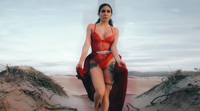 a woman in a red bodysuit walking on a beach