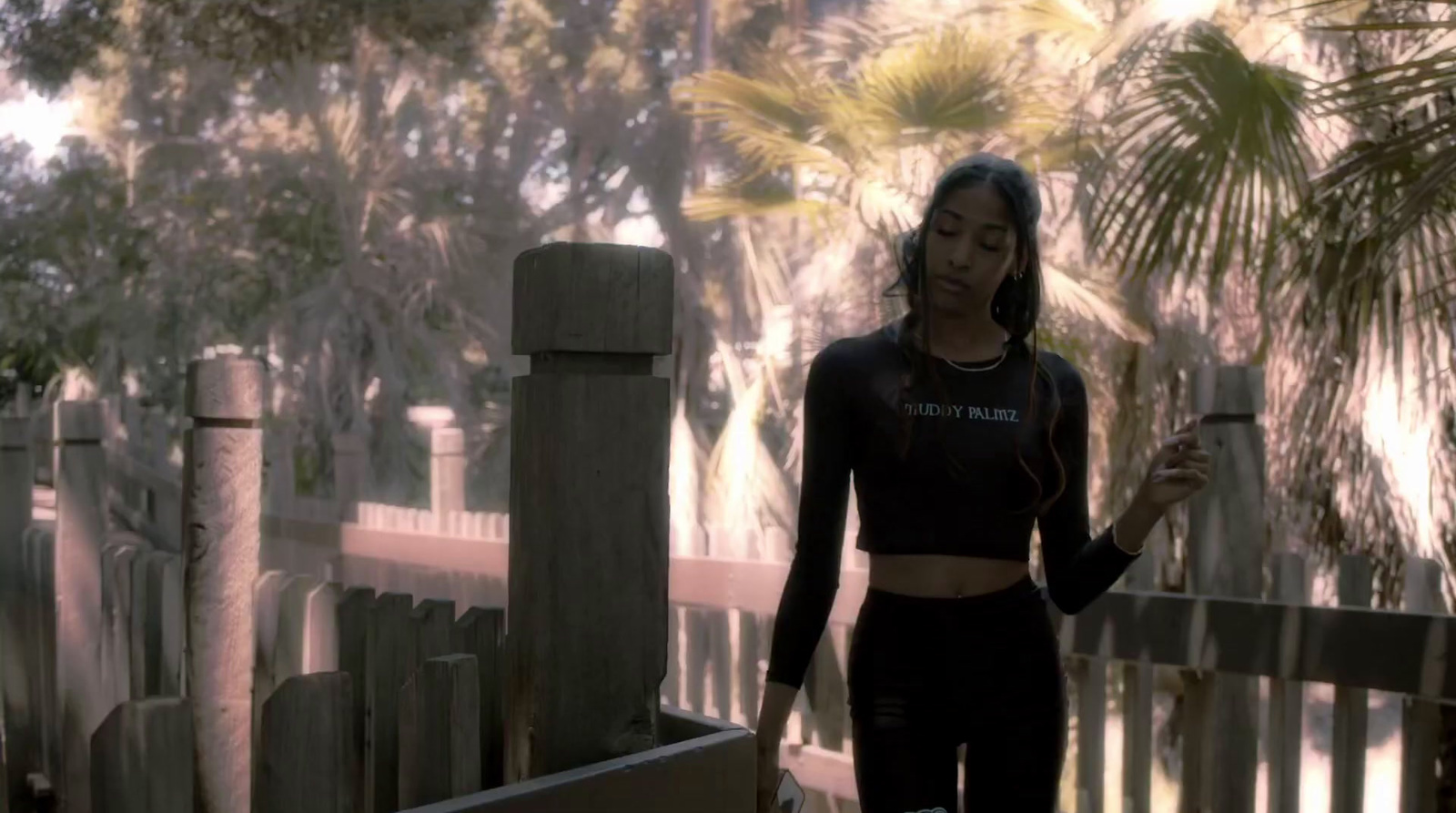 a woman in a black top and leggings holding a cell phone