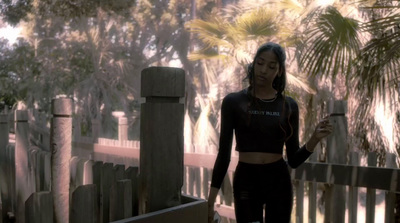 a woman in a black top and leggings holding a cell phone