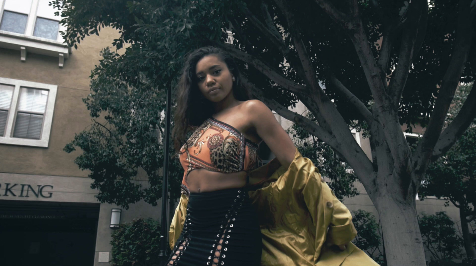 a woman in a corset standing in front of a tree