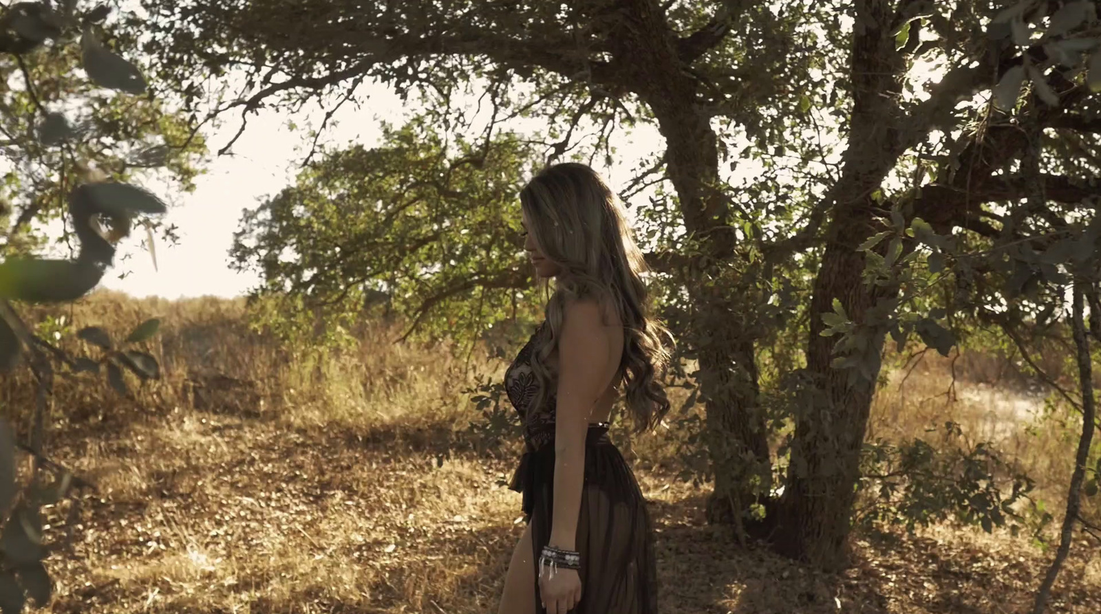 a woman standing in a field next to a tree