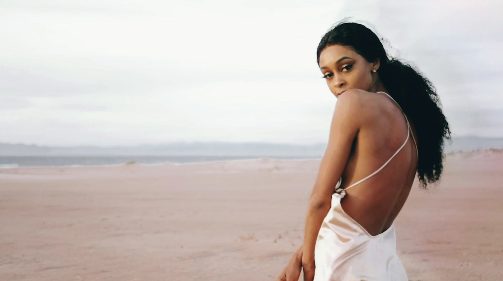 a woman in a white dress standing on a beach