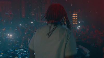 a man with dreadlocks standing in front of a dj set