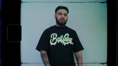 a man with a beard standing in front of a wall