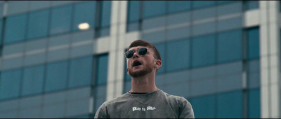 a man with sunglasses standing in front of a tall building