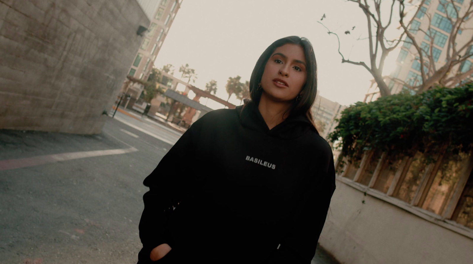 a woman in a black hoodie standing on a street