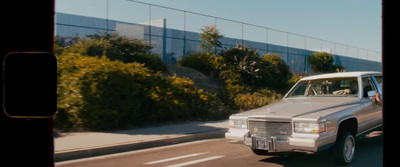 a white car driving down a street next to a tall fence