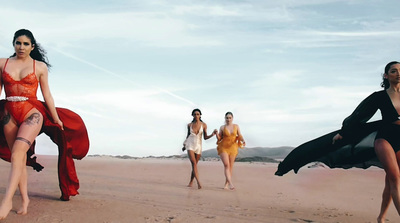 a group of women walking across a sandy beach