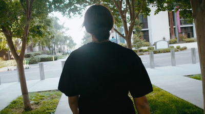 a woman walking down a sidewalk next to trees